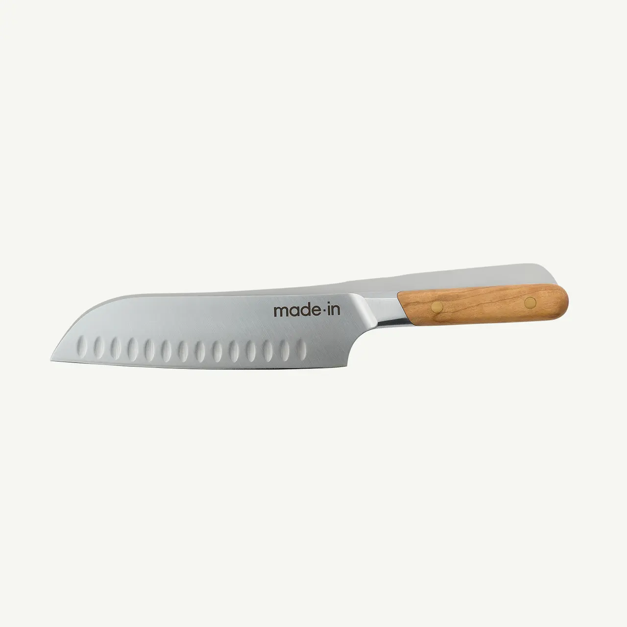 A stainless steel chef's knife with a wooden handle and dimples on the blade is displayed against a white background.