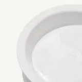 A close-up view of an empty white plate on a light background.