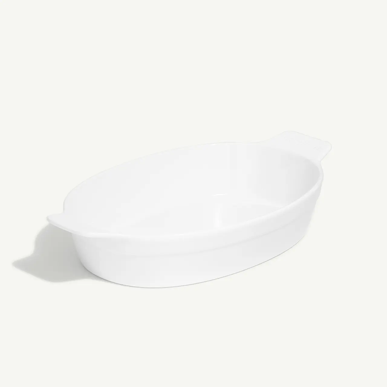 A white ceramic oval baking dish on a plain background.