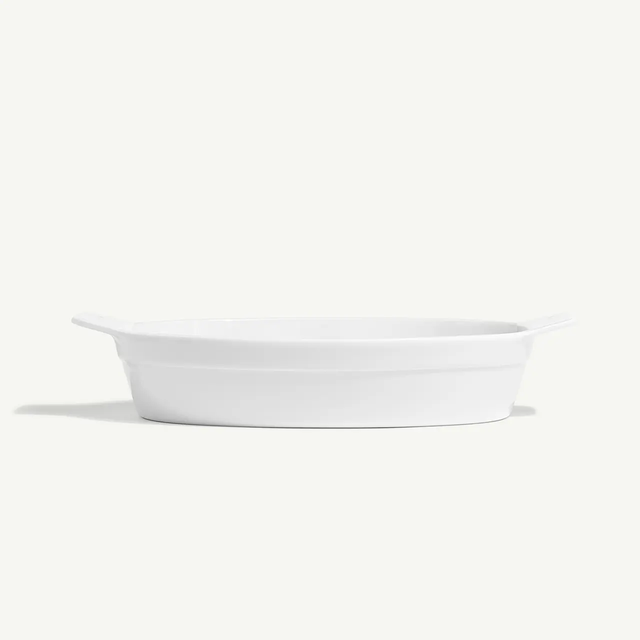 A simple white oval baking dish is displayed against a plain background.