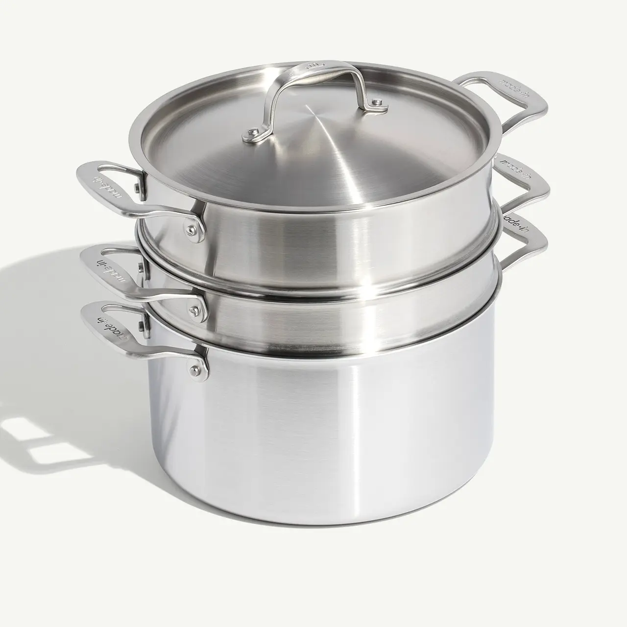 Stacked stainless steel pots with lids, showcasing cookware design.