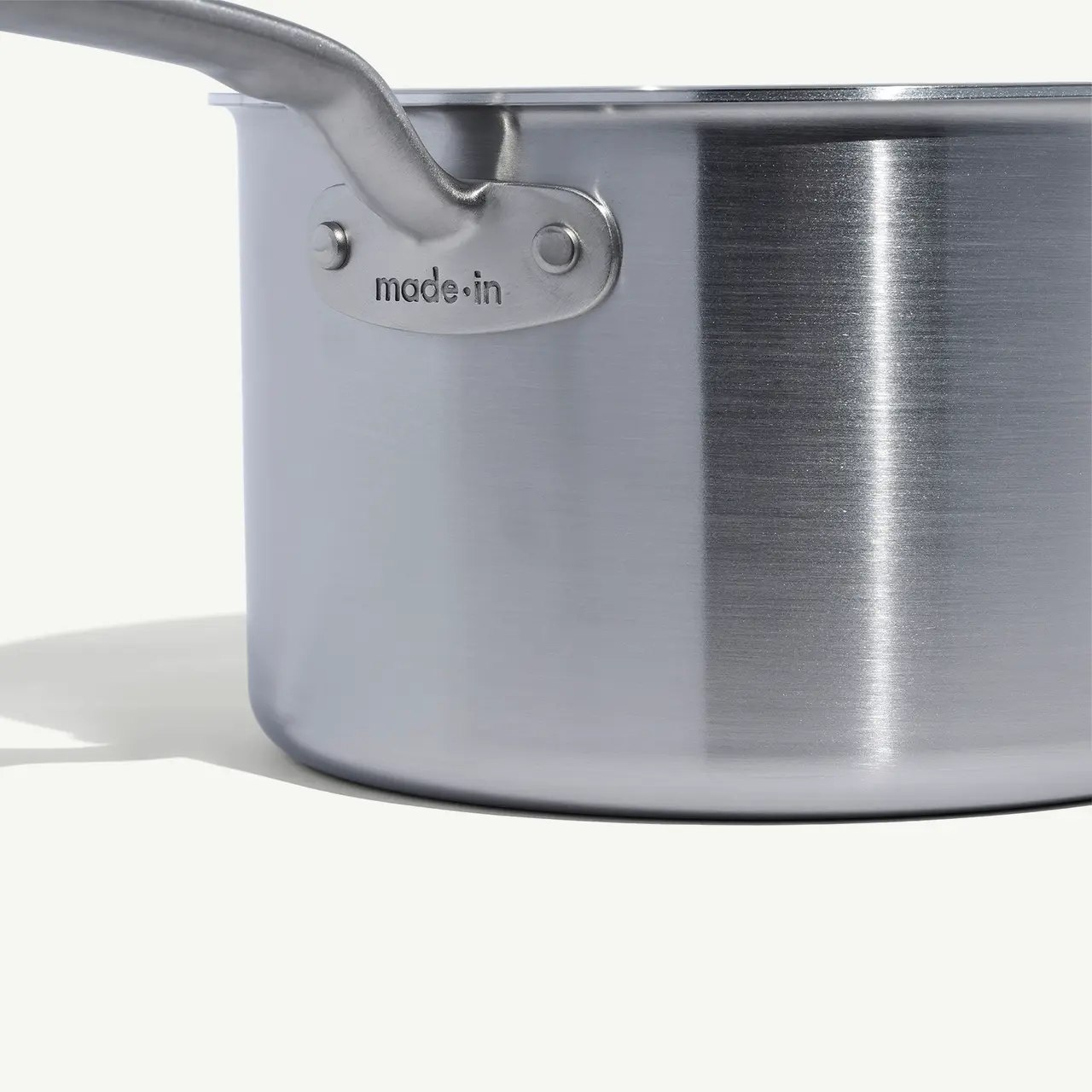 A stainless steel pot with the inscription "made in" on its handle, set against a white background.