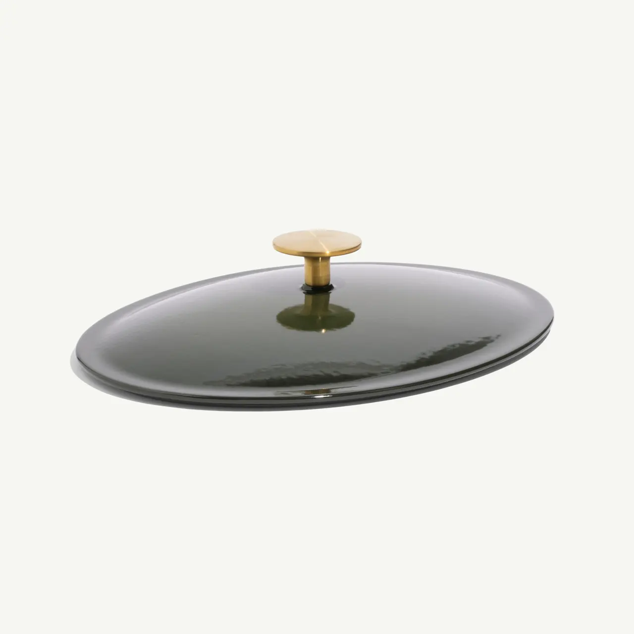 A dark green oval lid with a gold handle positioned at the center.