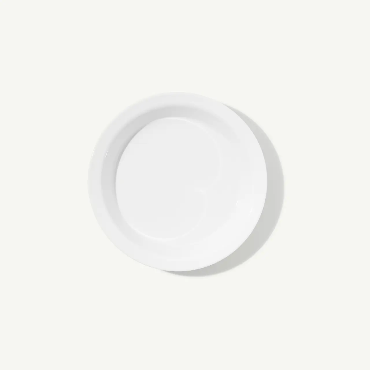 A plain white plate is centered on a light background.