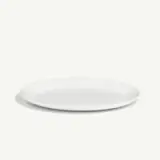 A simple white round plate is centered on a light background.