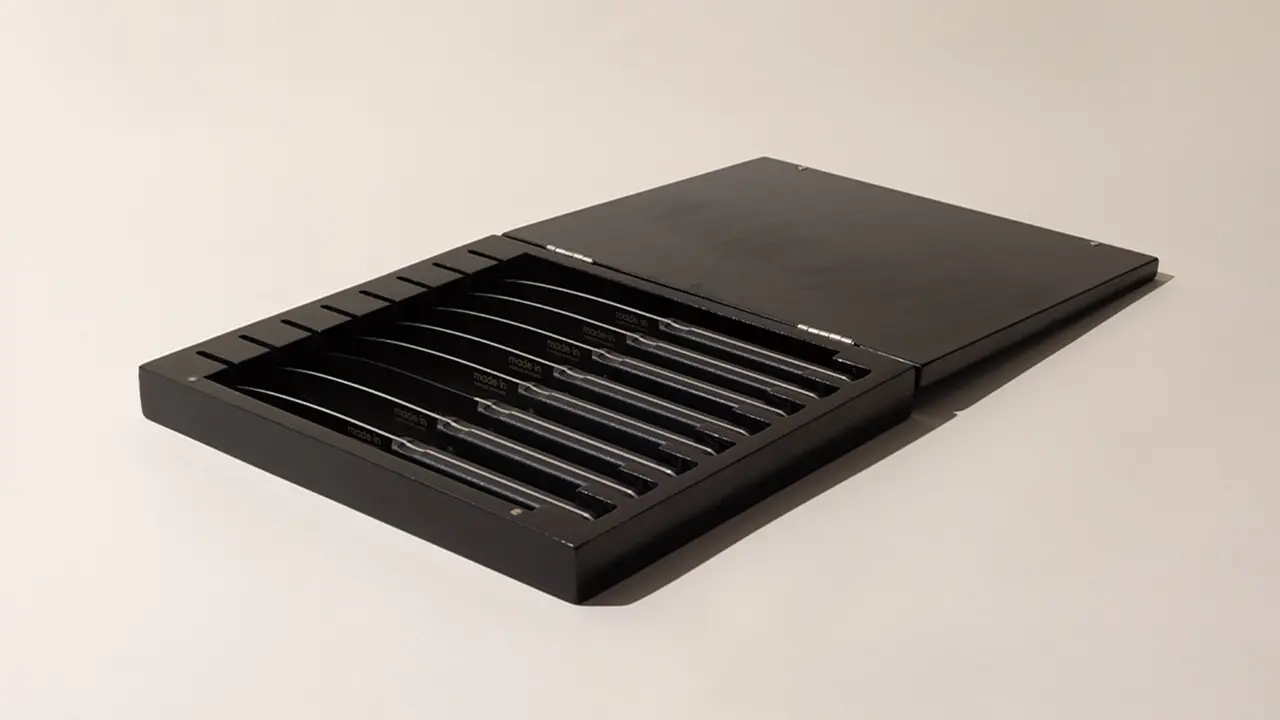 A sleek, modern black cutlery tray with silver utensils neatly arranged in slotted compartments.