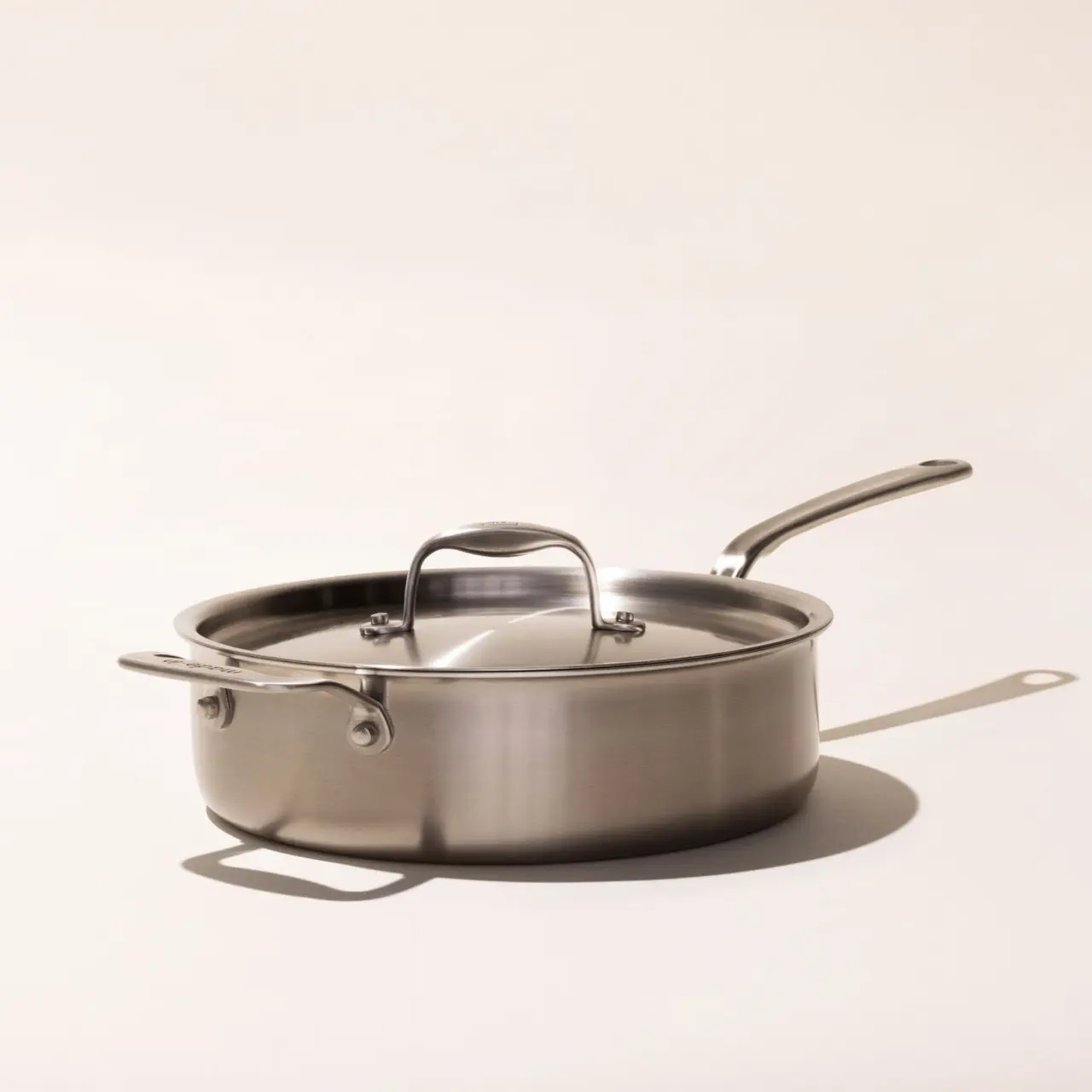 A stainless steel saucepan with a lid and a long handle appears on a neutral background.