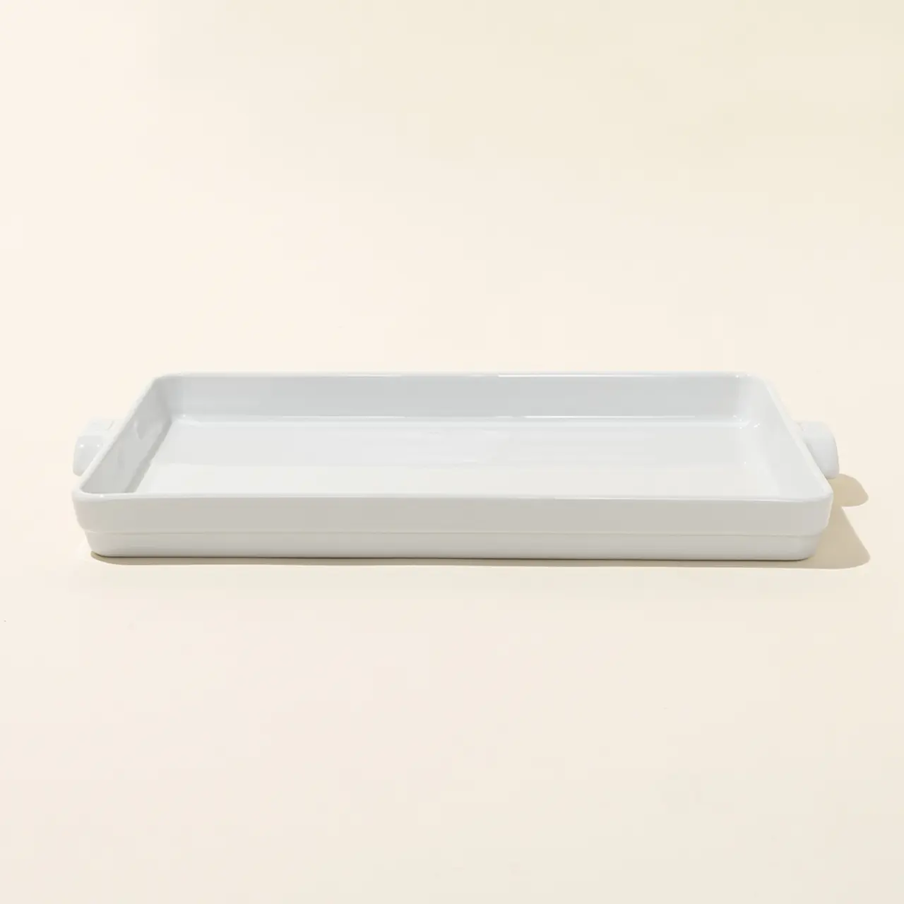 A simple white rectangular ceramic dish rests on a neutral backdrop.