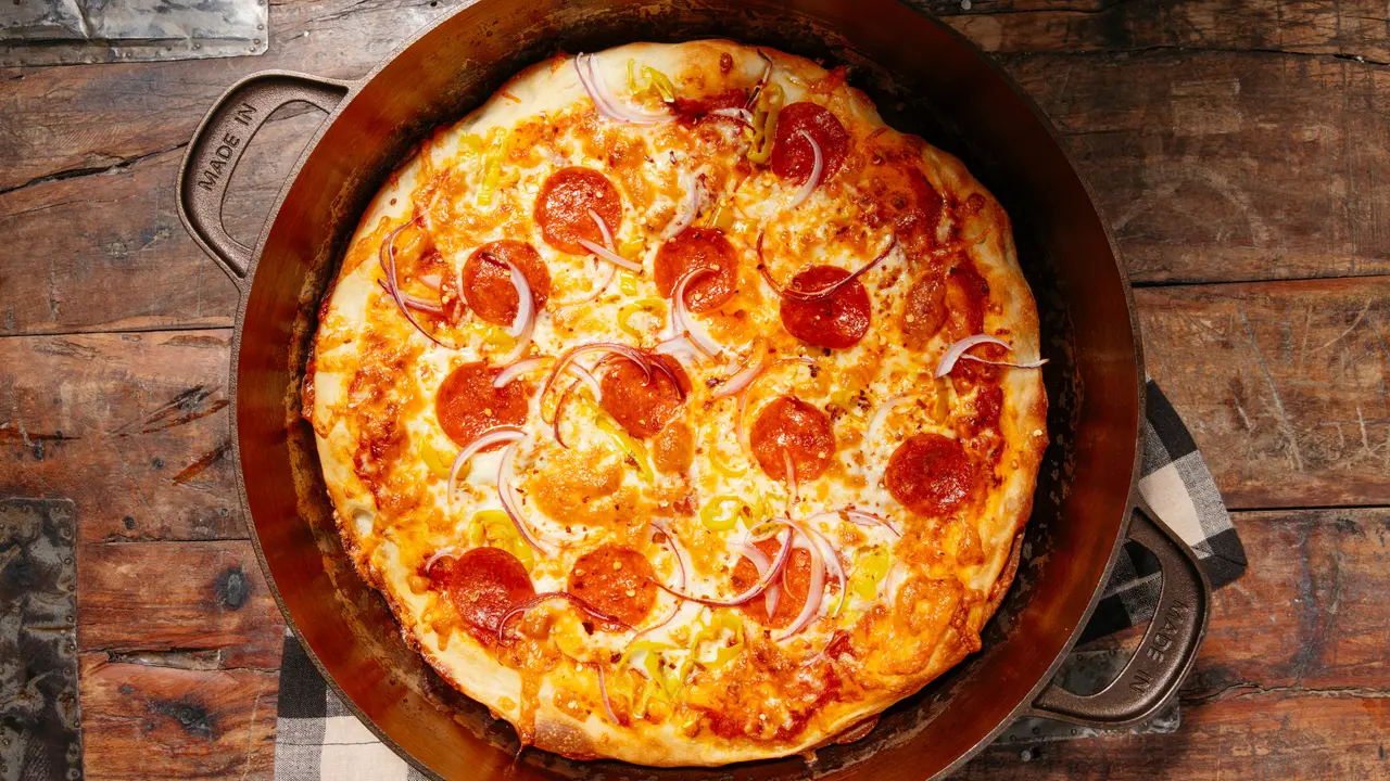 Pepperoni pizza with red onion in a Made In Cast Iron Skillet.