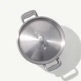 A stainless steel pot with a lid is presented from a top-down perspective on a light background.