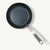 A new frying pan with a non-stick surface and stainless steel handle lies against a plain background.