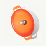 An orange circular skillet with a silver center and handles casts a shadow on a light surface.