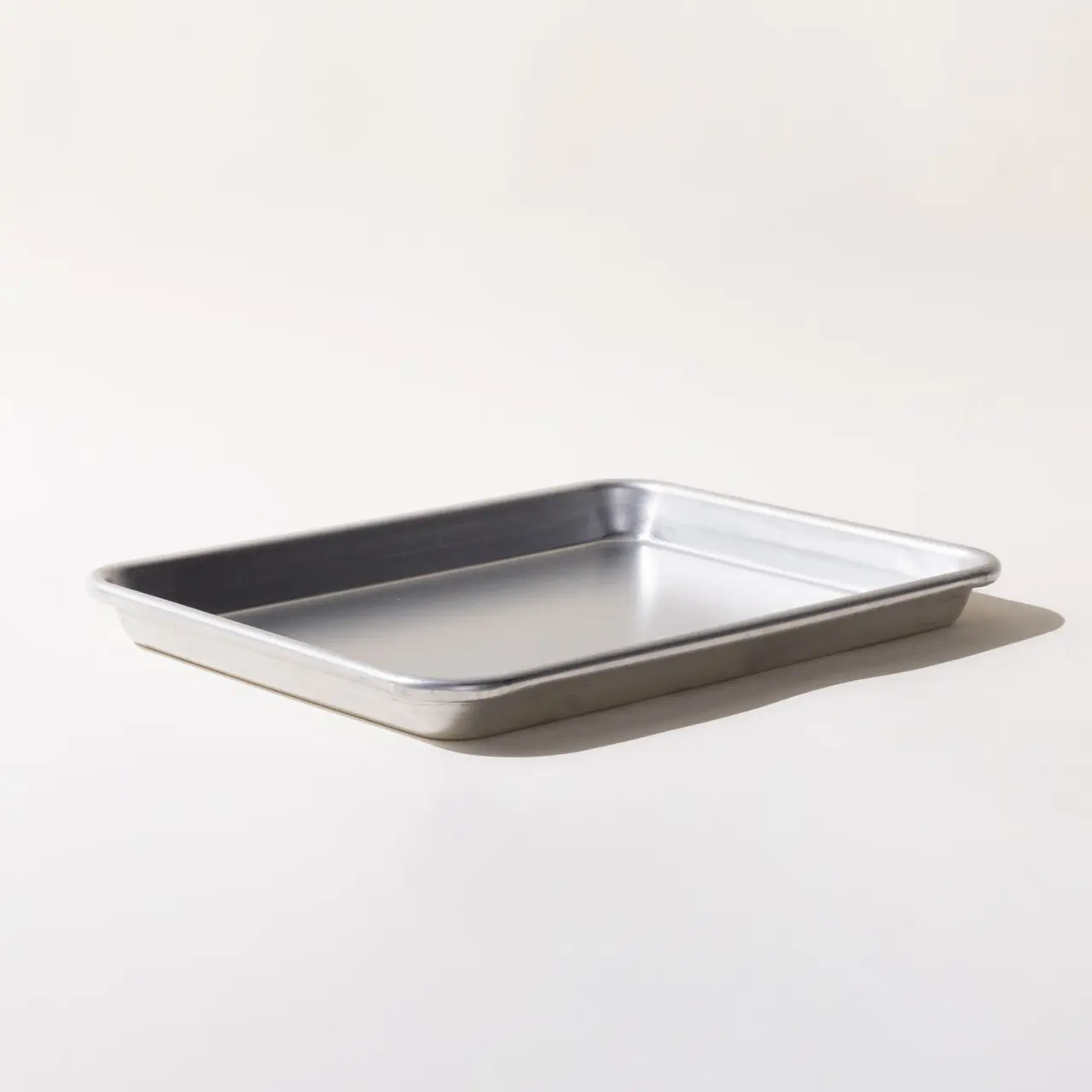 A rectangular metal baking sheet is placed on a white surface with a light shadow casting to the side.
