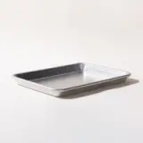 A rectangular metal baking sheet is placed on a white surface with a light shadow casting to the side.
