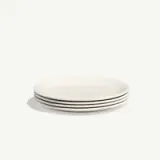 A stack of four simple white plates with a subtle edge design on a plain background.