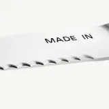 A close-up view of a serrated knife blade featuring the text "MADE IN" prominently displayed.