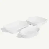Three white baking dishes in varying shapes and sizes are arranged on a light background.