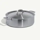 A stainless steel pot with a lid, placed on a neutral background.