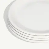 A stack of clean white plates is neatly aligned on a light background.