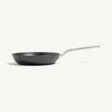 A black frying pan with a stainless steel handle is displayed against a light background.
