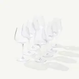 Several empty wine glasses of varying shapes and sizes are arranged on a light surface casting soft shadows.