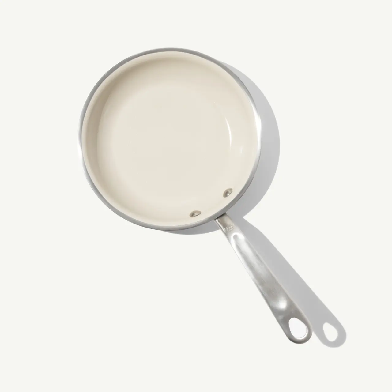 A white, non-stick frying pan with a stainless steel handle is shown from a top-down perspective.