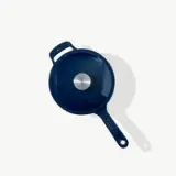 A blue frying pan with a lid viewed from above casting a light shadow on a plain surface.