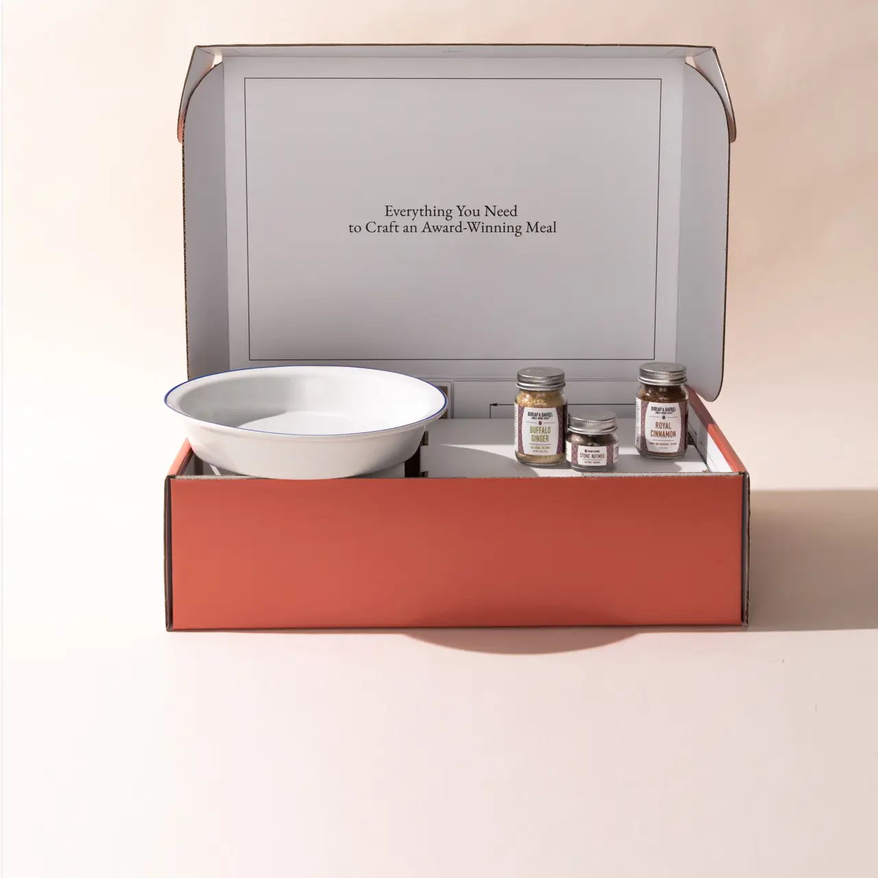 An open meal kit box containing a bowl and spice jars, with the text "Everything You Need to Craft an Award-Winning Meal" inside the lid.