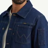 A close-up of a man wearing a dark blue denim jacket with a white shirt underneath.