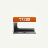 A metal paper weight features an orange top with the word "TEXAS" printed in white.