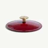 A round, glossy red lid with a brass knob in the center.