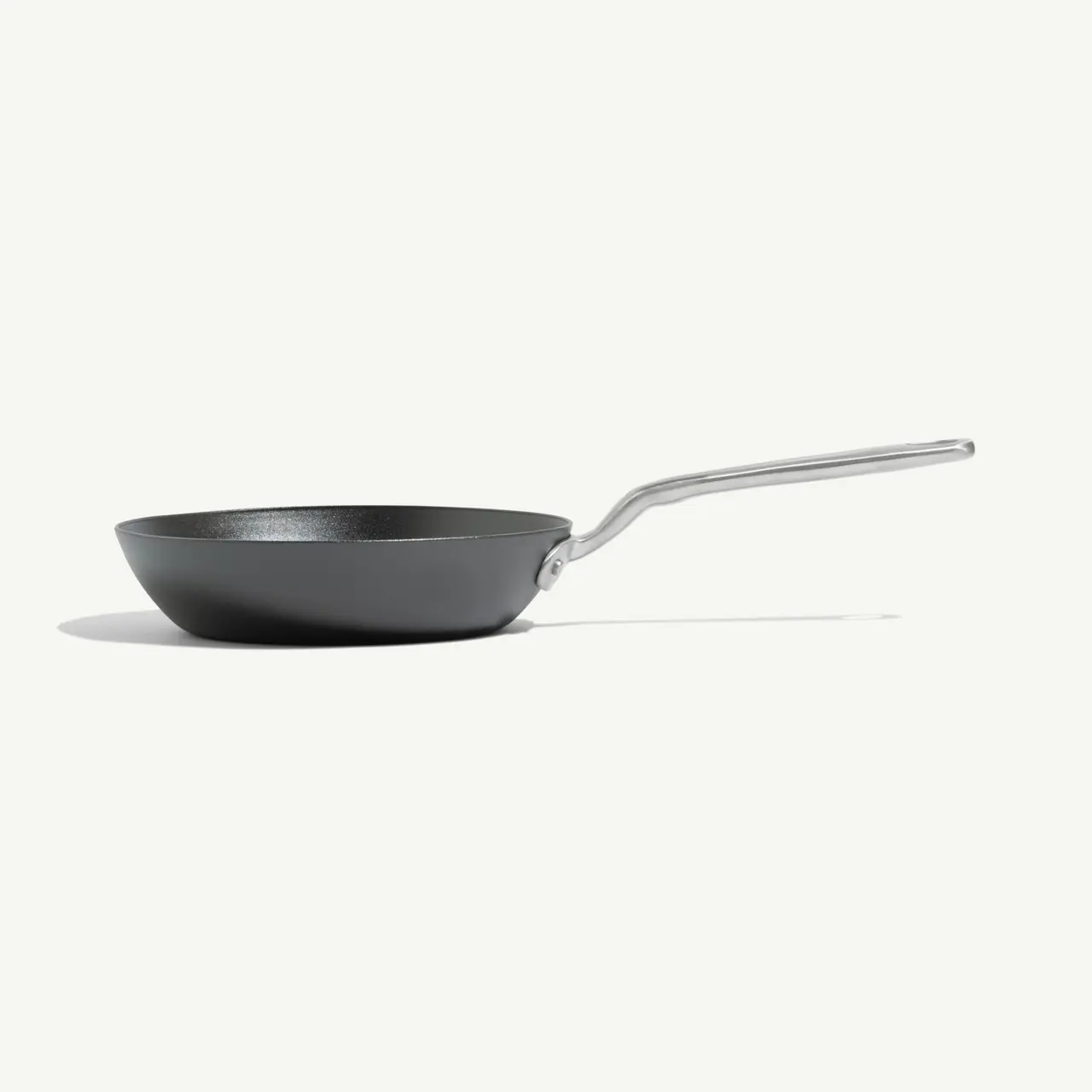 A black frying pan with a sleek metallic handle is shown on a light background.