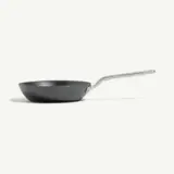 A black frying pan with a sleek metallic handle is shown on a light background.