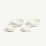 Four white ceramic bowls of varying sizes are arranged in a row on a light background.