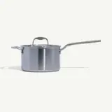 A stainless steel saucepan with a long handle and a lid against a white background.
