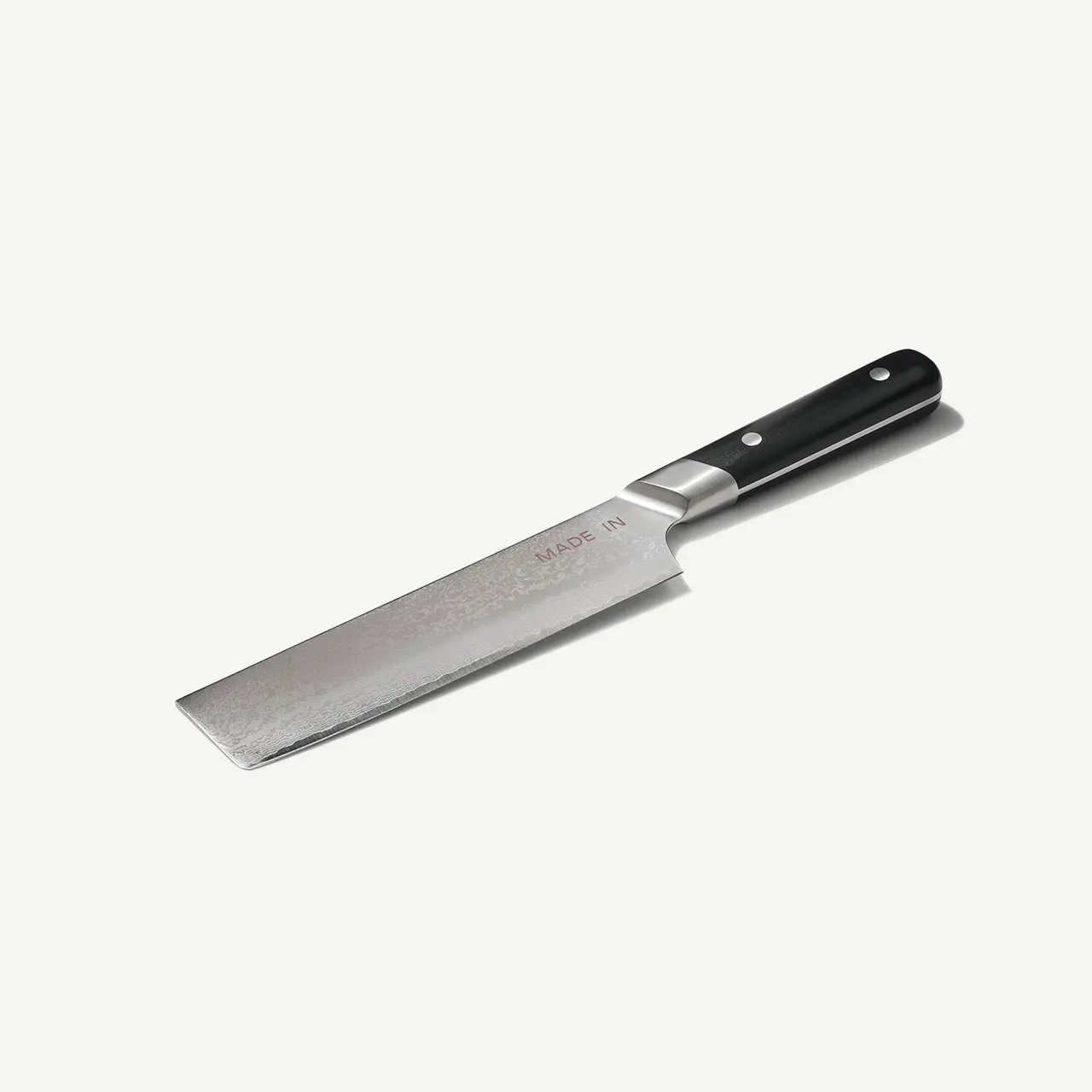 A stainless steel chef's knife with a black handle lies isolated on a white background.