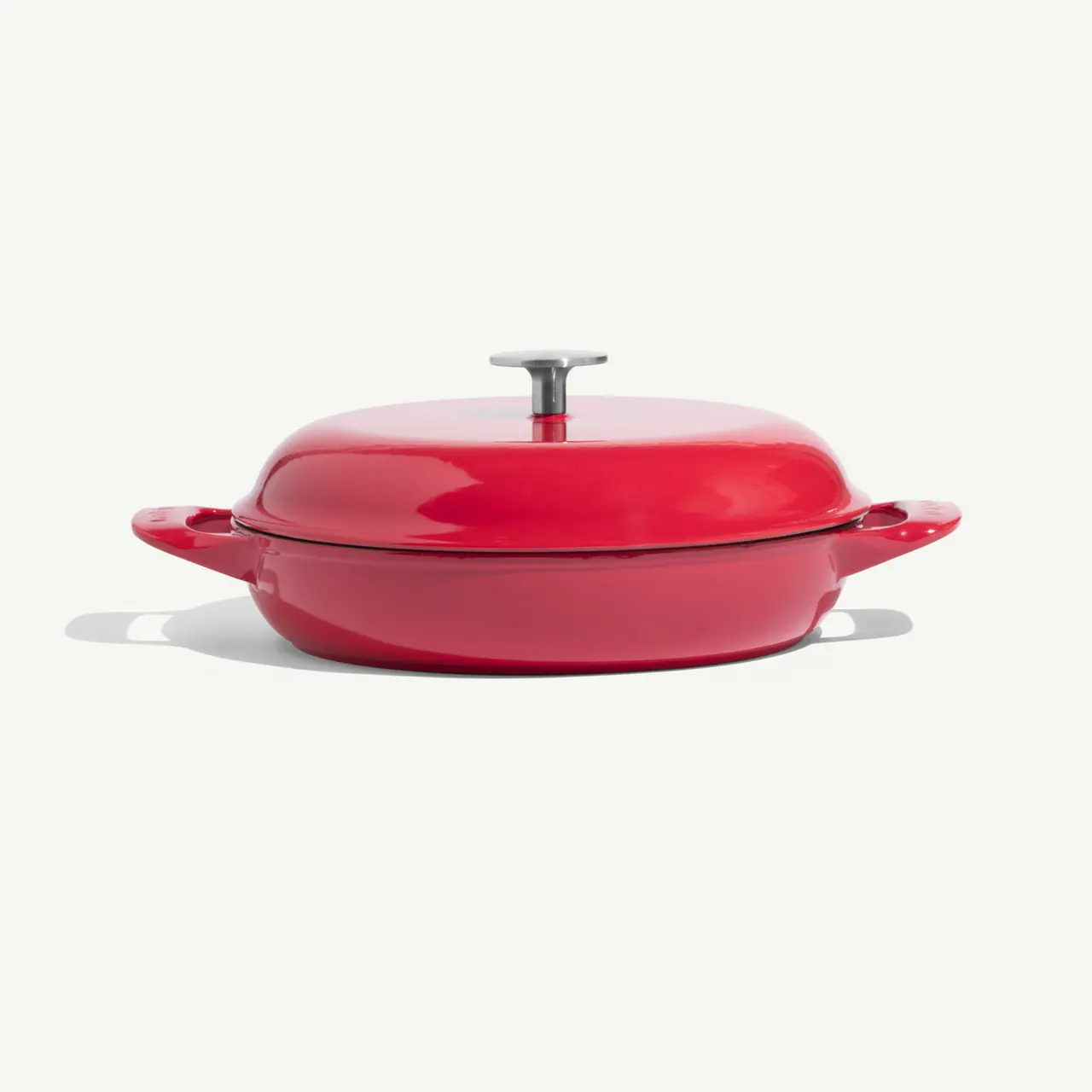 A vibrant red cooking pot with a flat lid and two handles.
