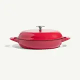 A vibrant red cooking pot with a flat lid and two handles.