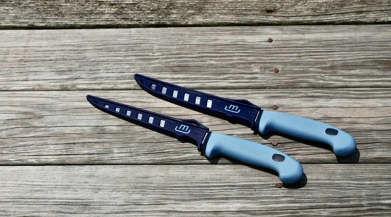 Two blue-handled kitchen knives lie on a wooden surface.