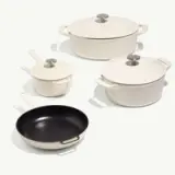 A variety of cookware is displayed, including two lidded pots, a small saucepan, and a skillet, featuring a mix of light-colored and black finishes.