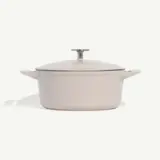 A cream-colored enameled cast iron Dutch oven is centered on a white background.