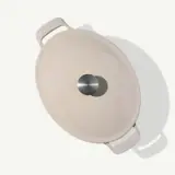 A beige-colored tortilla press is displayed from above, showcasing its circular pressing surface and sturdy handles.