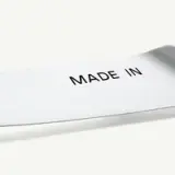 A close-up of a stainless steel blade with the words "MADE IN" printed on it.