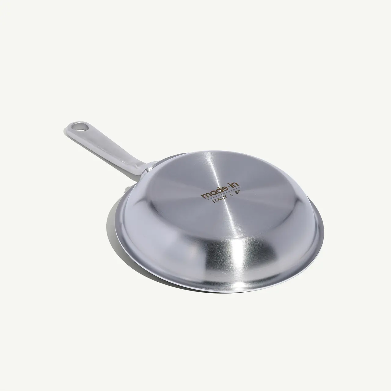 A stainless steel pan with a long handle is displayed against a light background.