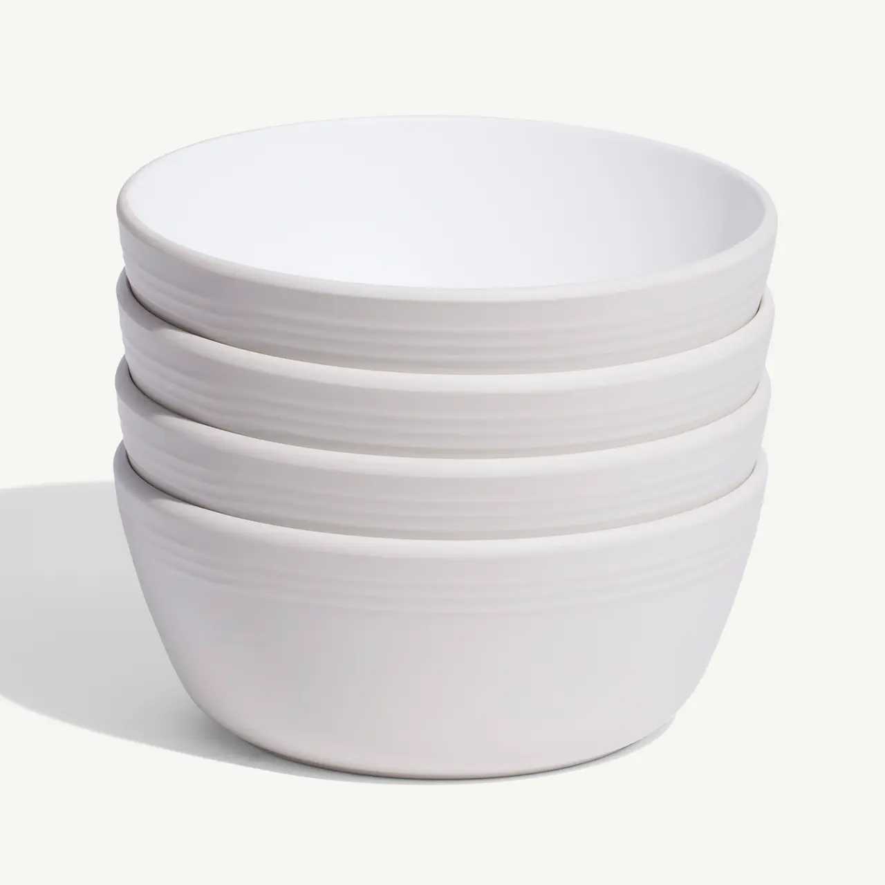 A stack of white ceramic bowls is neatly aligned against a plain background.