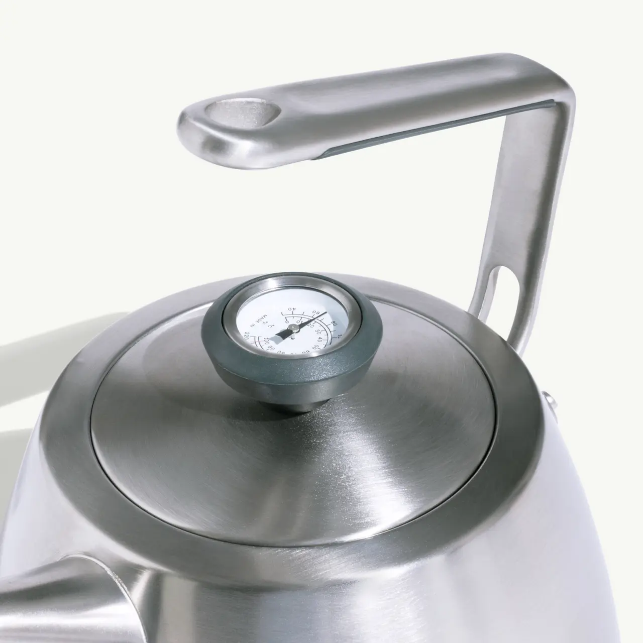 A stainless steel kettle features a round body and a temperature gauge on the lid.