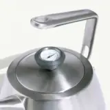 A stainless steel kettle features a round body and a temperature gauge on the lid.