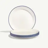 Four stacked white plates with blue rims, accompanied by a single plate standing upright in the background.
