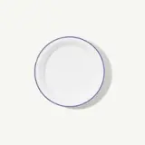 A white, round, ceramic plate with a thin blue rim is shown against a light background.