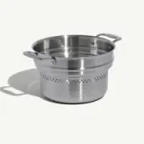 A stainless steel pot with an integrated strainer sits on a white background.